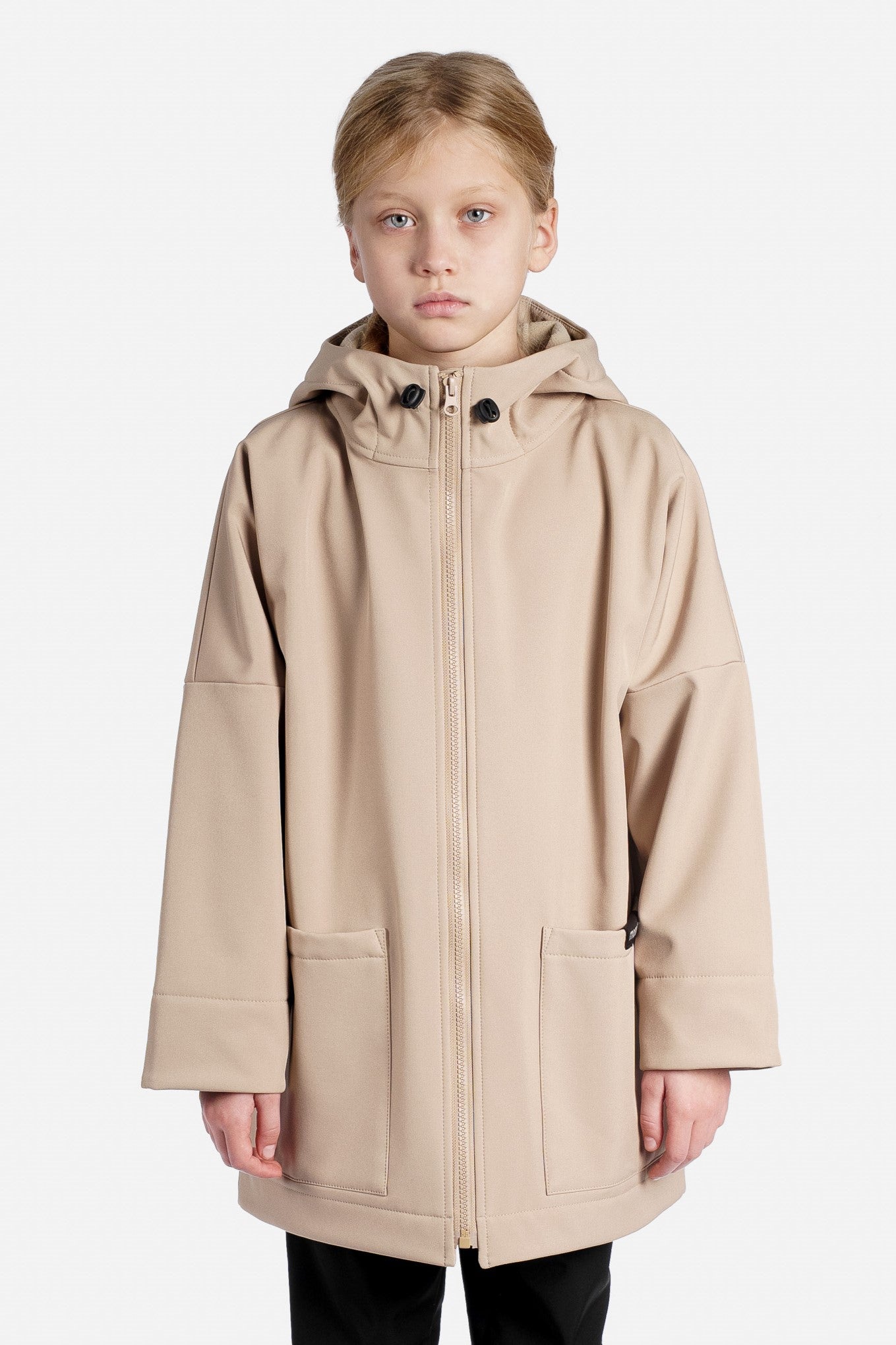 Child wearing a beige rain jacket on a white background