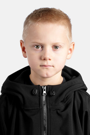 Young boy wearing a black hoodie against a white background