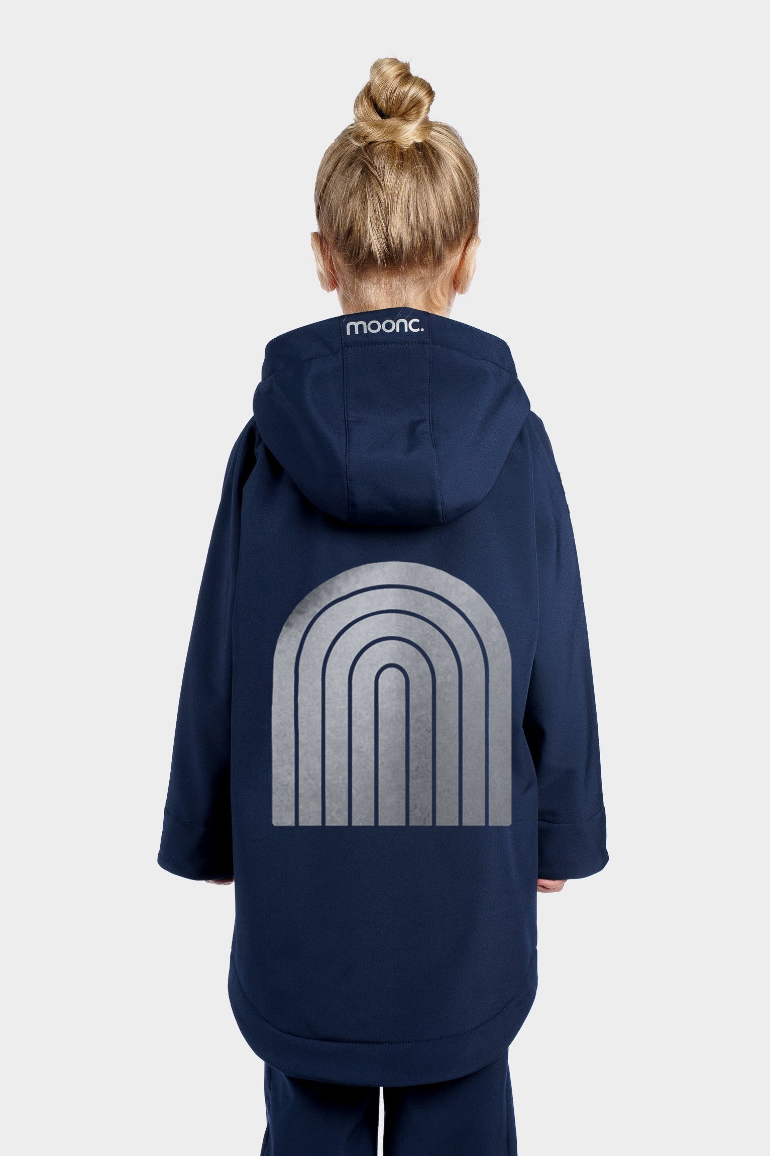 Person wearing a navy blue coat with a logo on the back against a white background