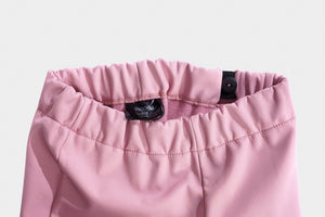 Close-up of pink pants with a brand label on a light gray background