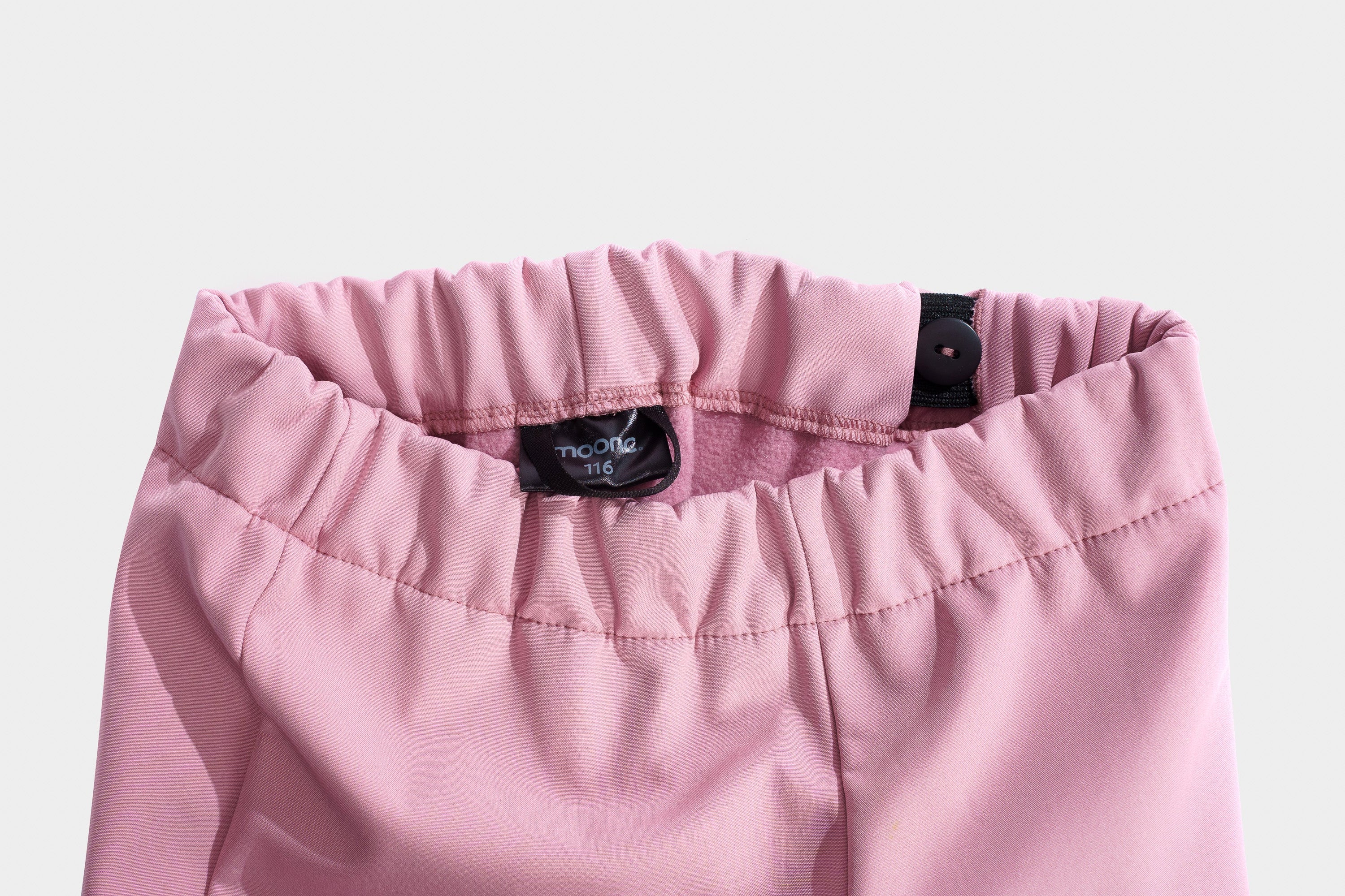Close-up of pink pants with a brand label on a light gray background