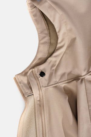 Close-up of a beige jacket with a zipper and button on a light background