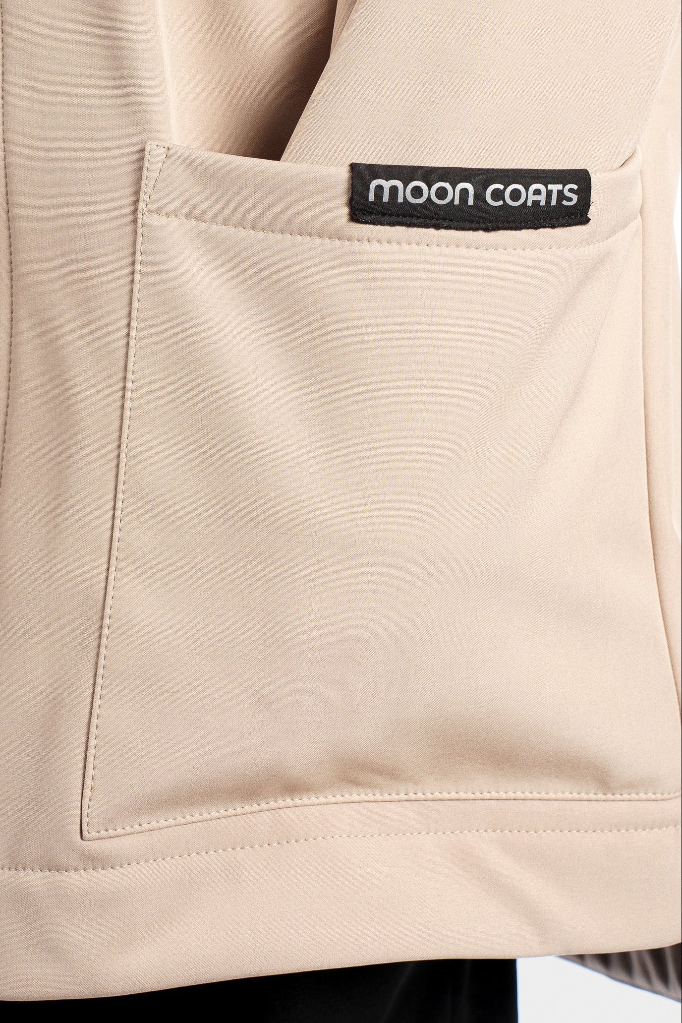Beige jacket with a visible 'Moon Coats' logo on a white background