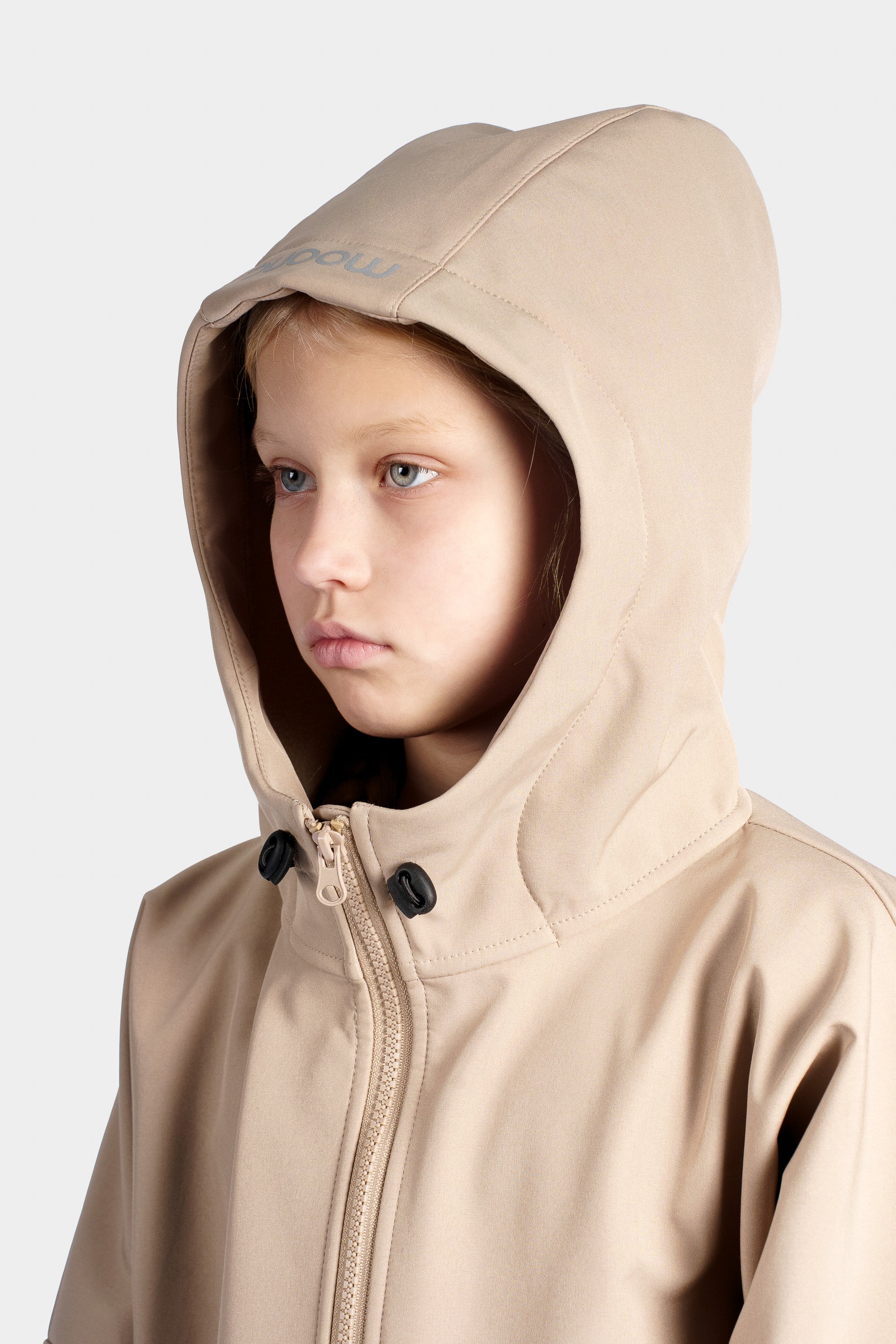 Child wearing a beige hooded jacket with a brand logo on a white background